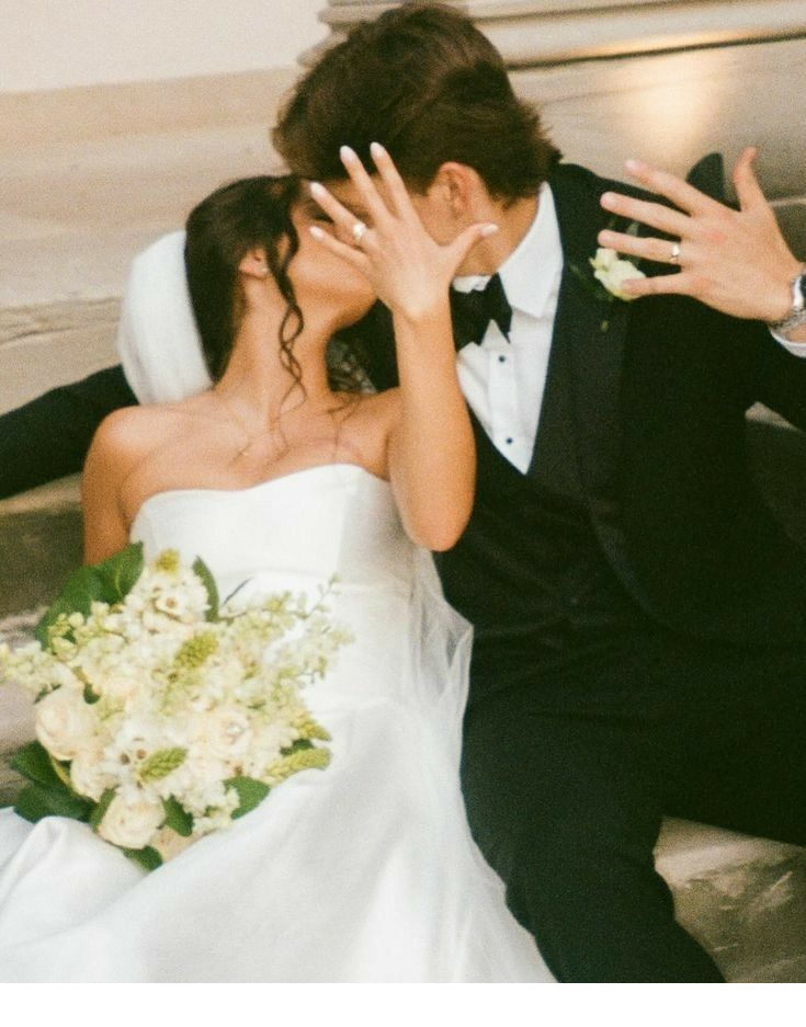 A bride and groom sharing a candid, laughing embrace on stone steps after their wedding ceremony
